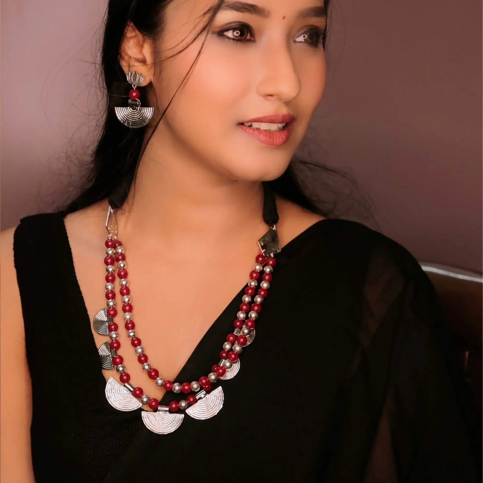 Woman wearing black sleeveless top with layered red and silver bead jewelry for festival styling